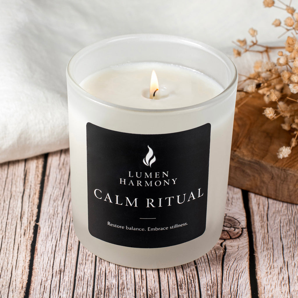 Candle labeled 'Lumen Harmony Calm Ritual' on a wooden surface with dried flowers.
