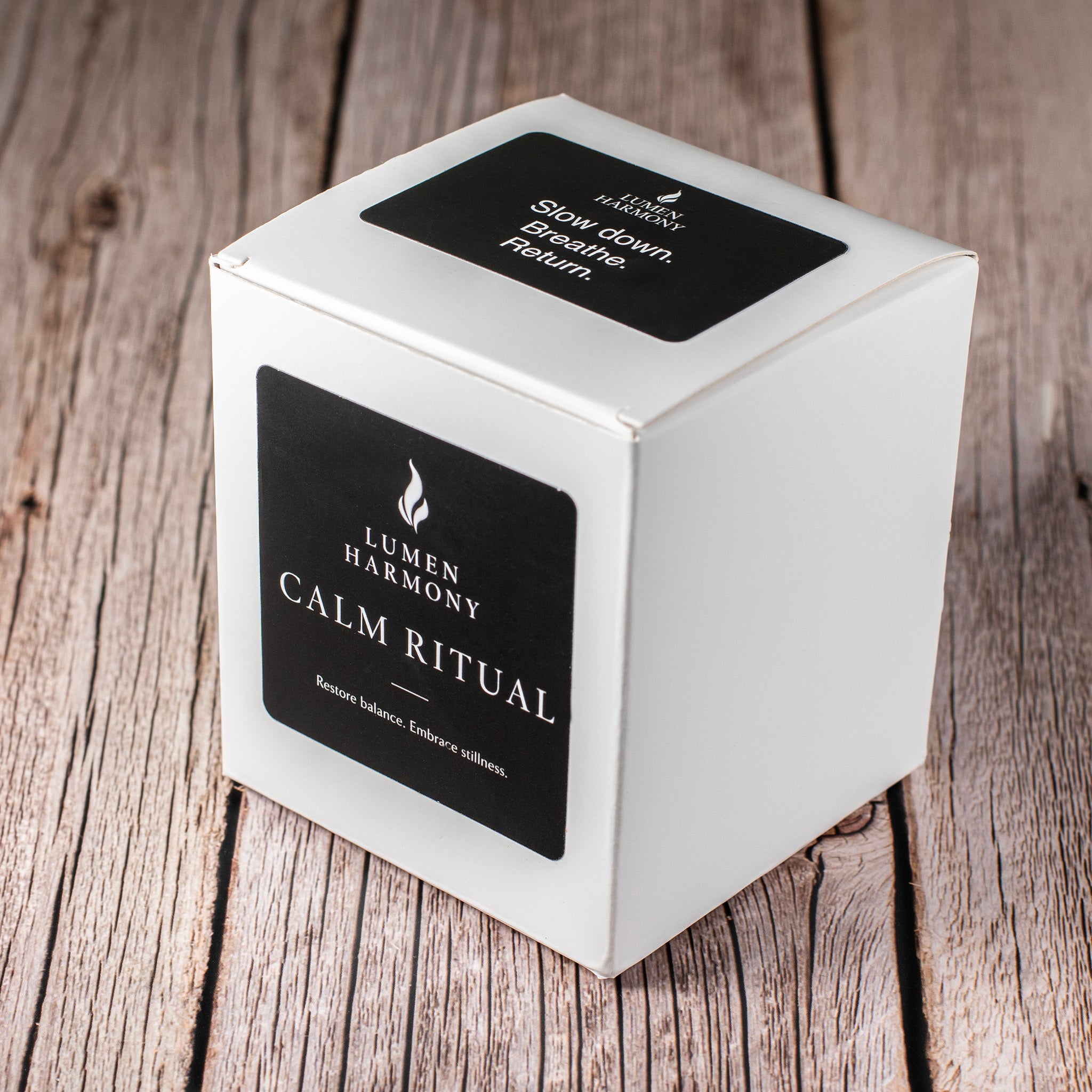 Candle packaging with 'Lumen Harmony' branding on a wooden surface