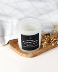 A candle called "in loving memory of Mom" over a wooden table and tiny flowers as decoration