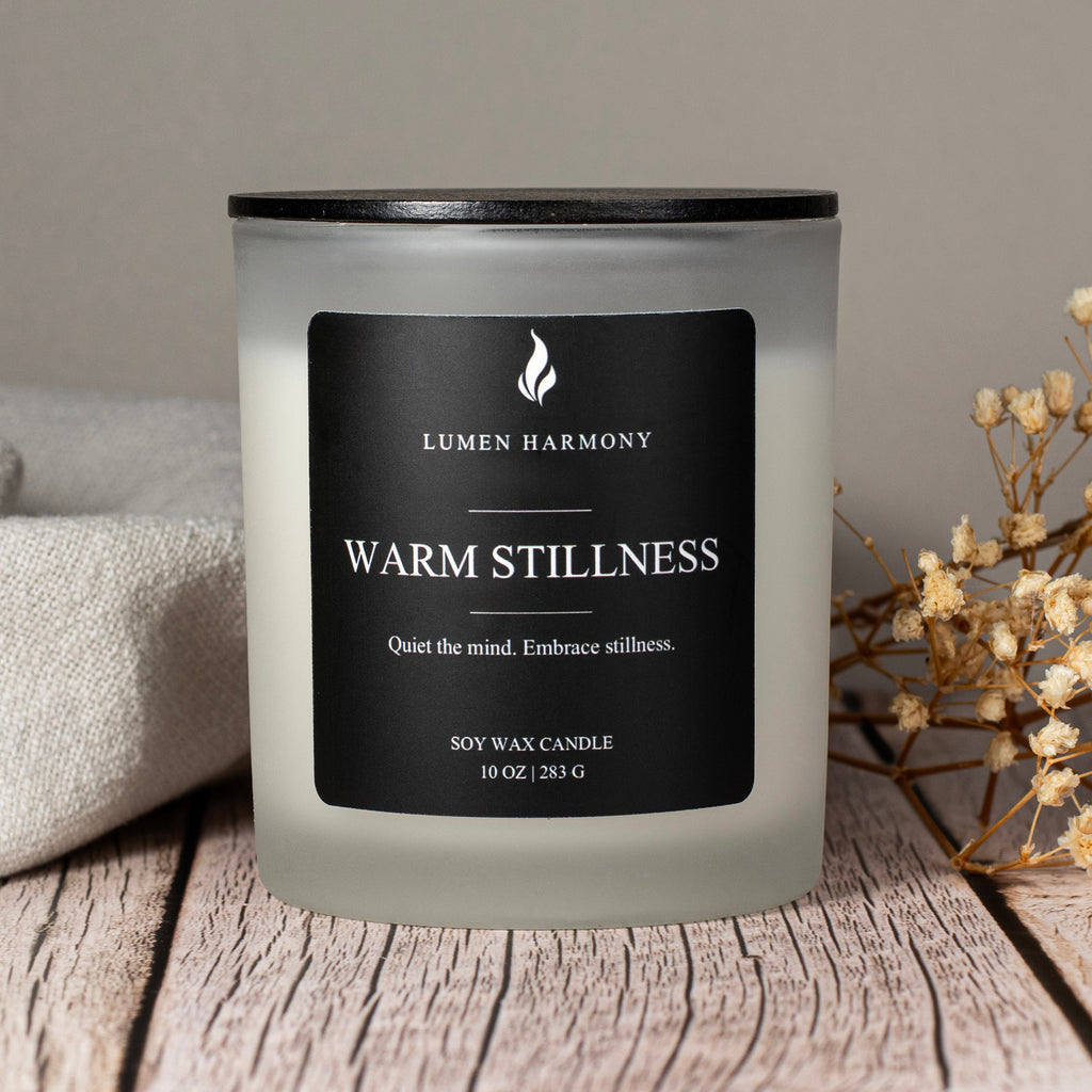 Lumen Harmony candle labeled 'Warm Stillness' on a wooden surface with a neutral background.
